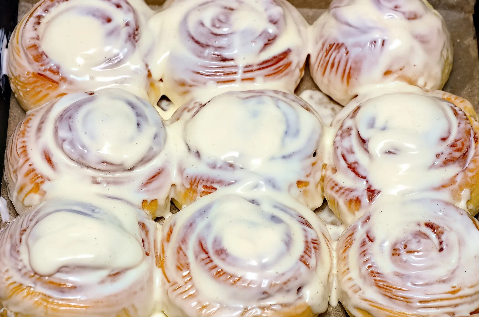 A pan of homemade cinnamon rolls covered in white icing.