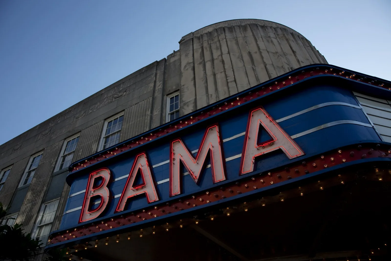 The neon Bama marquee on the Historic Bama Theatre against the evening sky on Greensboro Avenue in downtown Tuscaloosa.