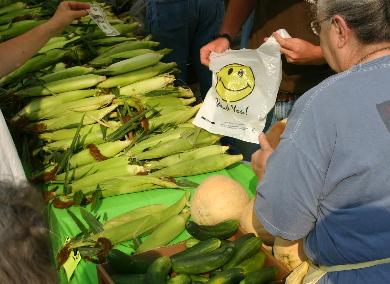 A vendor bags sweet corn for a customer at a farmers market stand in Alabama.