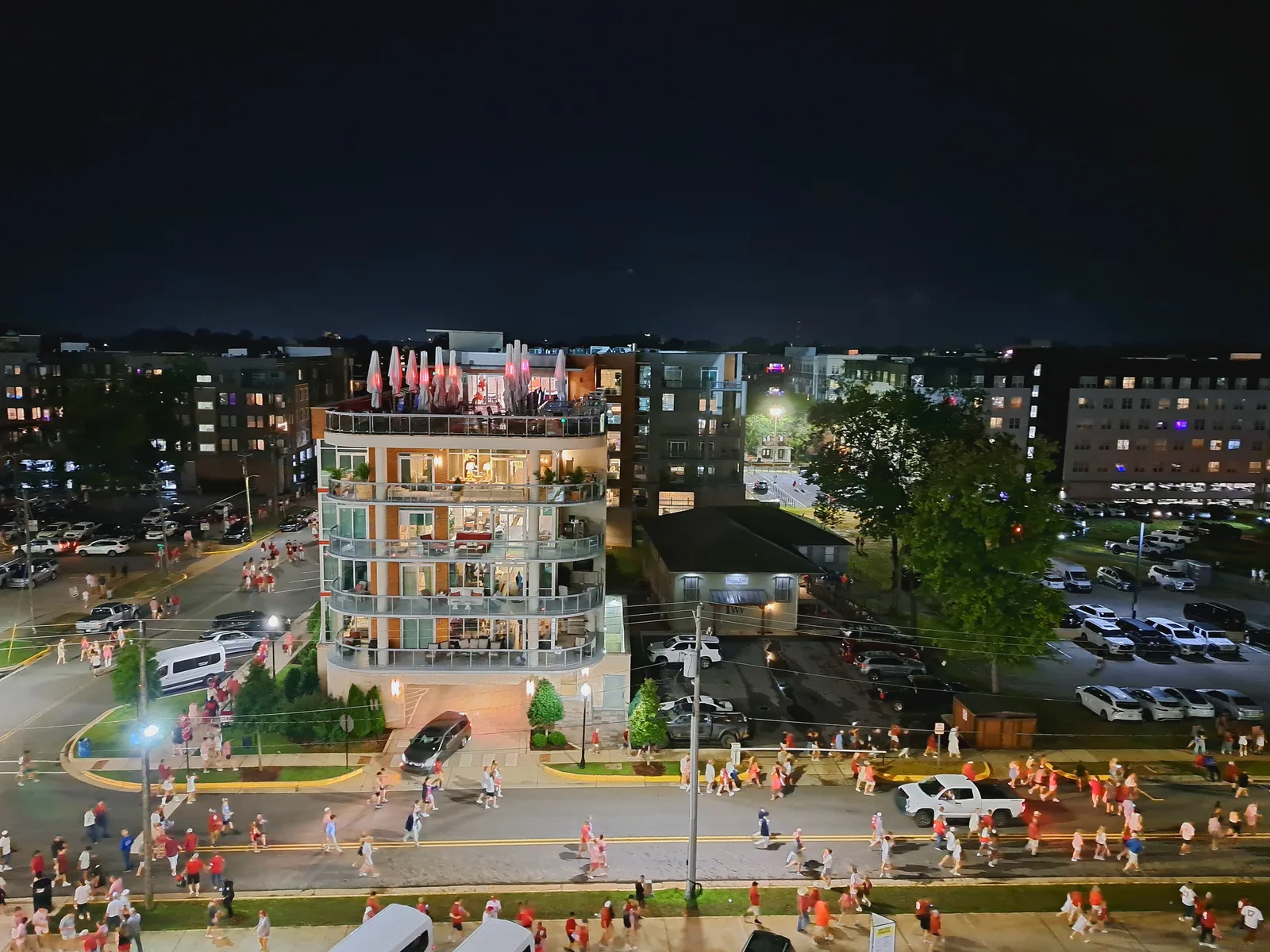 Crowds in crimson walk past apartment buildings in Tuscaloosa on a football night.