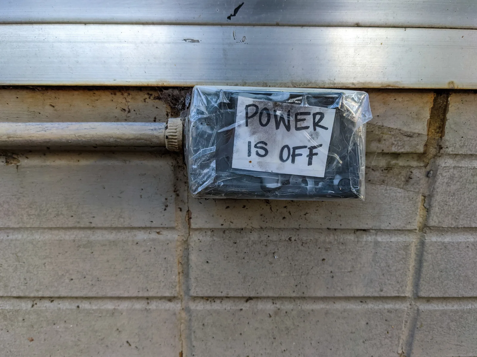 A handwritten "Power is off" sign is taped over an outdoor electrical box on a building in Tuscaloosa.