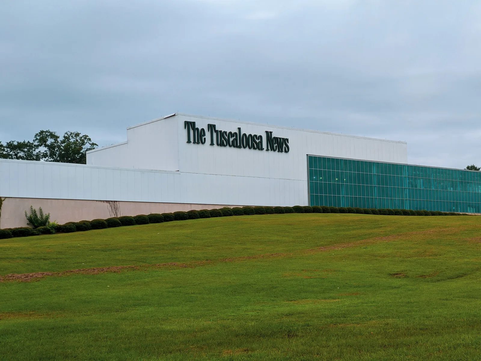 The Tuscaloosa News building on a grassy rise in Tuscaloosa; Alabama newspapers carry many of the county's legal notices.